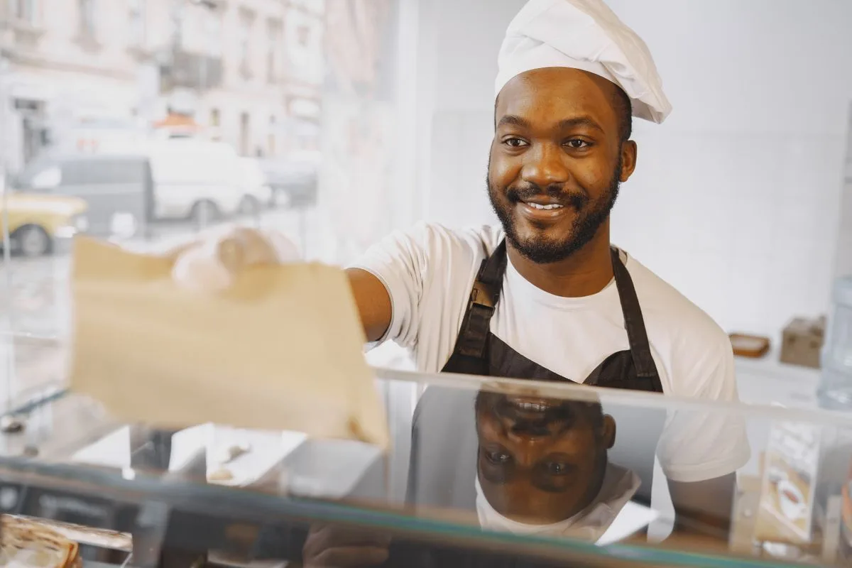 Un boulanger souriant accueille un client au comptoir
